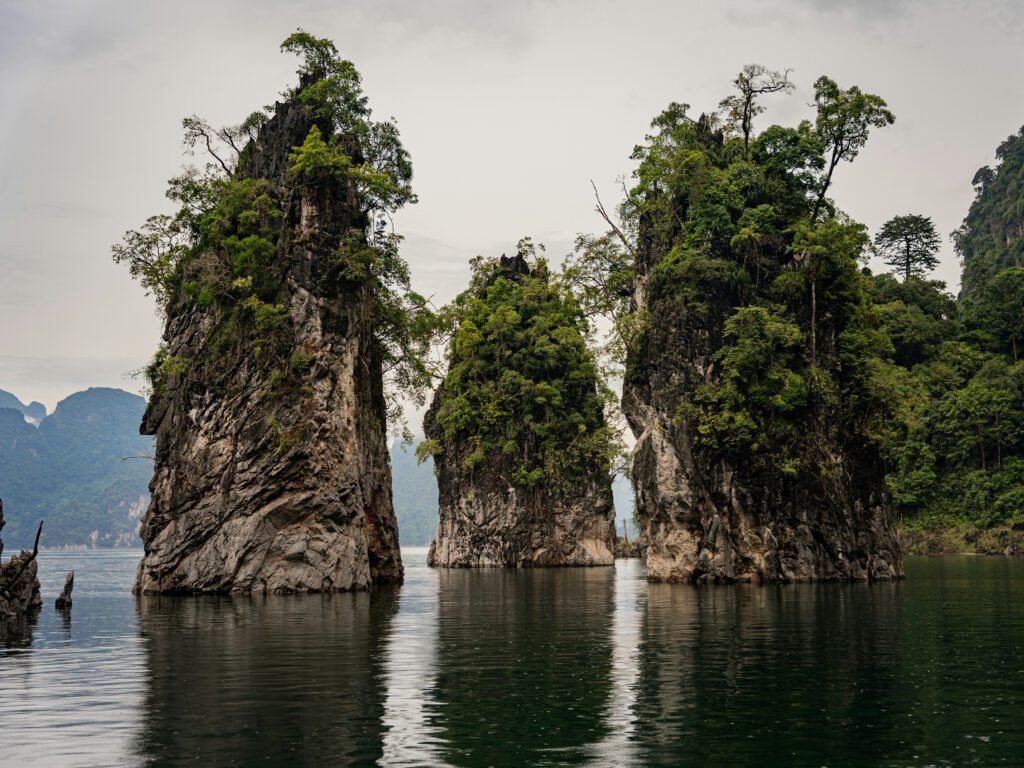 A photo of three tall rocks poking out of the sea in the Khao Sok National Park in Thailand. In the interview, Anthony Lambert mentions his desire to leave his job and go to Thailand for a year. However, life intervenes and he never makes it to Thailand.